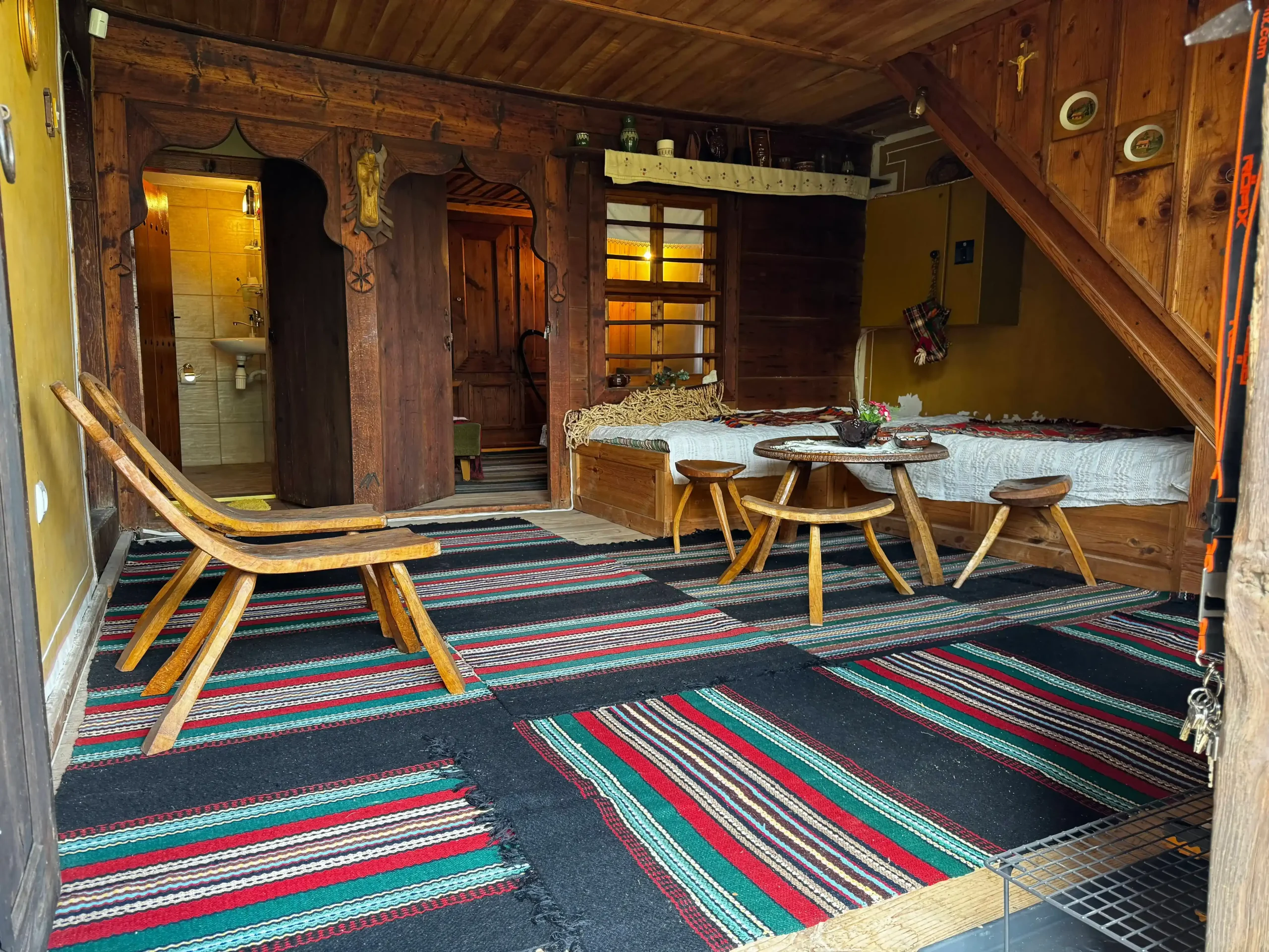 Large bedroom with bathroom and toilet first floor Traditional Bulgarian bedroom with wooden ceiling and colorful woven rug in a historic house in Koprivshtitsa.